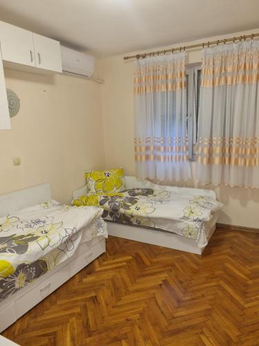 two beds in a room with wooden floors at Teodora Apartment in Ruse