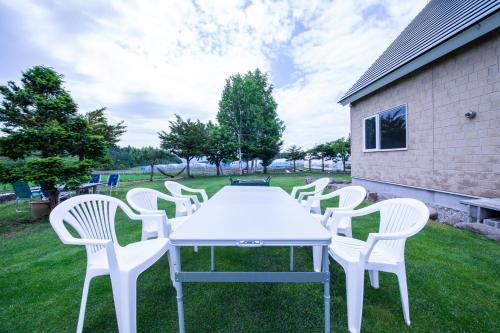 a group of white chairs and a table in the grass at The Sanfurano in Kami-furano