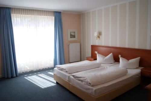 a bedroom with a bed and a large window at Hotel Pension Bellevue in Bad Doberan