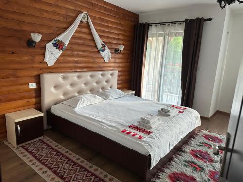 a bedroom with a bed and a wooden wall at Casa Maramureșană in Vişeu de Sus