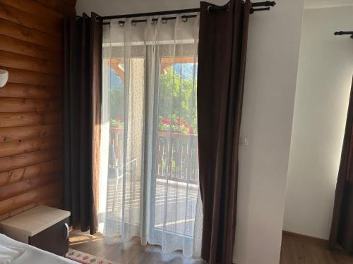 a bedroom with a window with curtains and a balcony at Casa Maramureșană in Vişeu de Sus