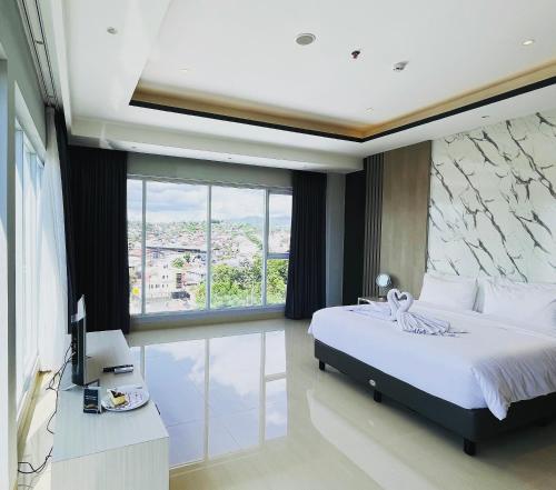 a bedroom with a bed and a large window at Rogers Hotel Manado in Pineleng