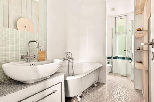 La salle de bains blanche est pourvue d'une baignoire et d'un lavabo. dans l'établissement Dinbnb Apartments I Characteristic Townhouse with Bathtub, à Bergen