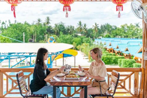 two women sitting at a table eating food at a restaurant at ห้างหุ้นส่วนจำกัด บ้านเถ้าแก่ in Ban Muang Baeng