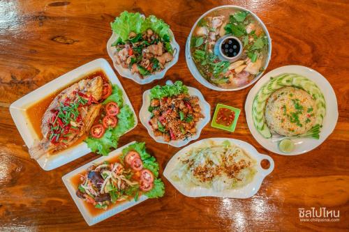 a group of plates of food on a wooden table at ห้างหุ้นส่วนจำกัด บ้านเถ้าแก่ in Ban Muang Baeng