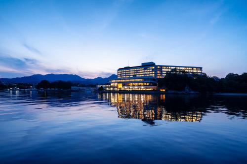 a building on the water with the lights on at Aki Grand Hotel & Spa in Miyajima