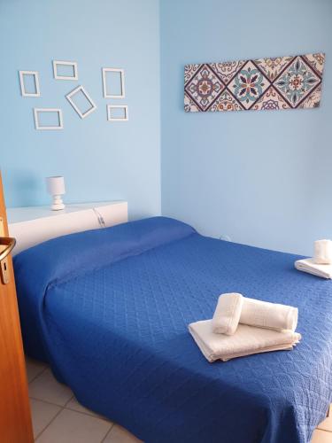 a blue bed with two towels on top of it at Villetta al mare in Marsala