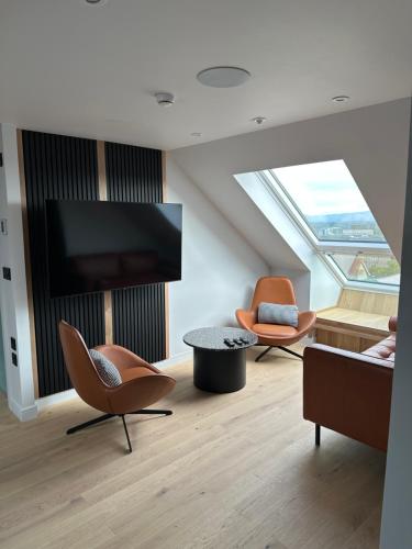 a living room with two chairs and a flat screen tv at Laurieston Penthouse in Grahamston