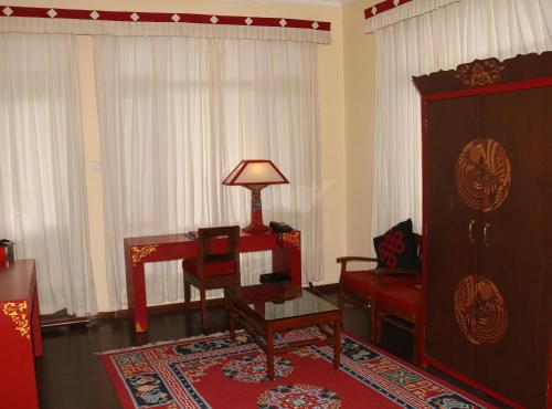 a living room with a desk and a chair and a lamp at New Serkong House in Dharamshala
