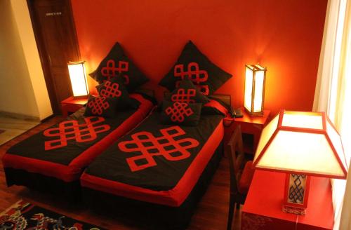 a bedroom with a bed with black and red pillows at New Serkong House in Dharamshala