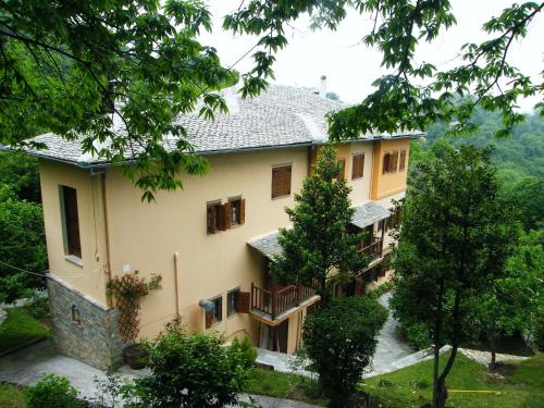 a large yellow house with a balcony and trees at Filoxenia in Tsagarada
