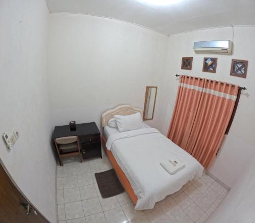 - une petite chambre avec un lit et une table dans l'établissement Mendiro Griya Syariah, à Ngemplak
