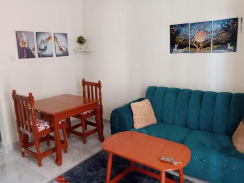 a living room with a blue couch and a table at Zuriel Homes 1 Bedroom apartment in Kakamega