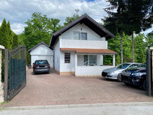a white house with cars parked in a driveway at Villa Gagula in Sarajevo
