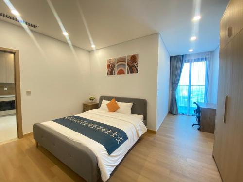 een slaapkamer met een bed en een bureau. bij Lancaster Luminaire Apartment Hotel in Hanoi
