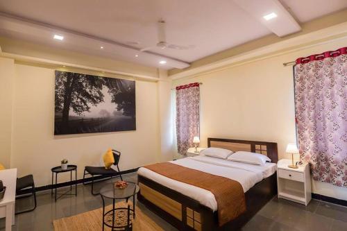 una camera con letto, tavolo e tende di The Banyan Tree Adobe a Kolhapur