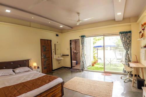 a bedroom with a bed and a desk and a window at The Banyan Tree Adobe in Kolhapur