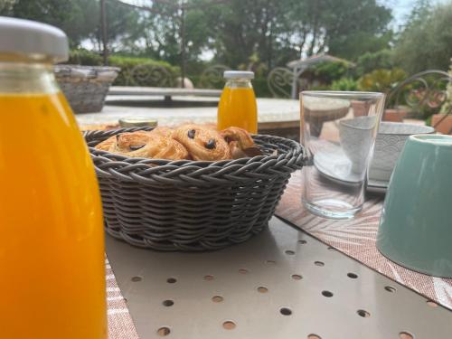 een broodmand op een tafel met sinaasappelsap bij La maison de la Cigale in Forcalqueiret