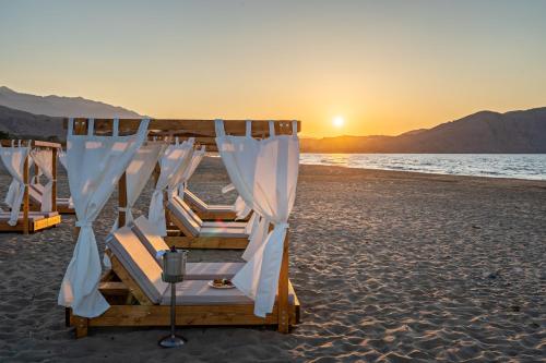a row of beds on the beach at sunset at Georgioupolis Suites & Aqua Park in Georgioupolis