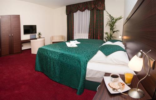 Pokój hotelowy z łóżkiem z zielonym kocem w obiekcie Hotel Princess w mieście Lednice