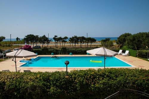 a large swimming pool with umbrellas and the ocean at Residence Costa Tirrena in Torrenova