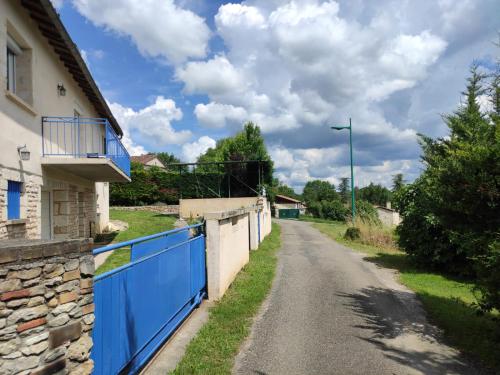 an empty street in a village with a blue fence at Maison de vacances La Quercynoise in Flaujac-Poujols