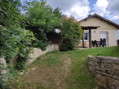 a house with a stone wall in front of it at Maison de vacances La Quercynoise in Flaujac-Poujols