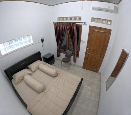 ein Schlafzimmer mit einem großen Bett und einer Holztür in der Unterkunft Griyo Mondoliko Homestay Jogja in Demangan