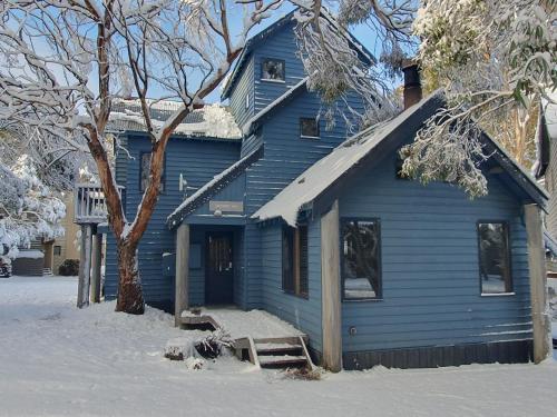 a blue house with a bench in the snow at SNOWED INN apartment in Dinner Plain