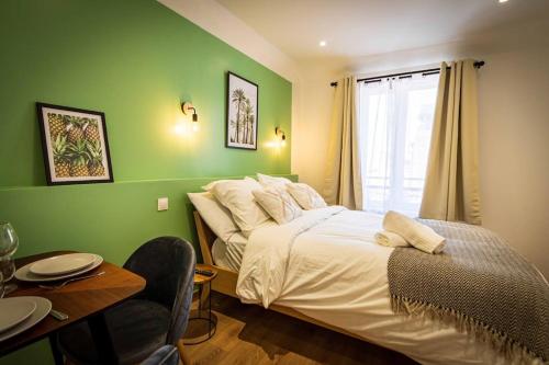 Dormitorio verde con cama y mesa con sillas en L'Albatros 001 - Hypercentre * Cosy * Wifi, en Saint-Quentin