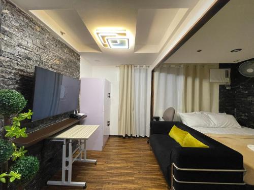 een woonkamer met een bank en een flatscreen-tv bij Tagaytay Vibe King Bed Suite near Alabang Muntinlupa in Manilla