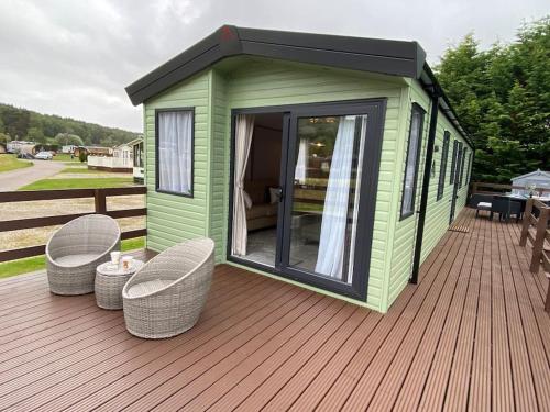 a green house with two chairs on a deck at Perfect for country lovers in Grantown on Spey