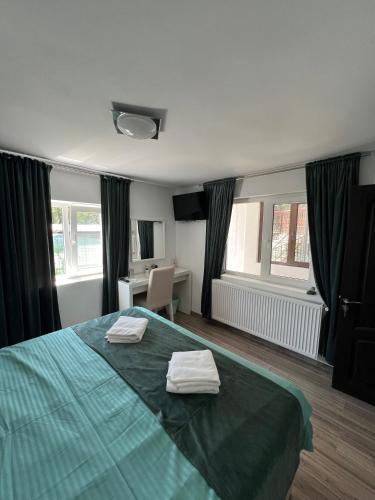 a bedroom with a green bed with two towels on it at Accommodation Casa Luca in Horezu