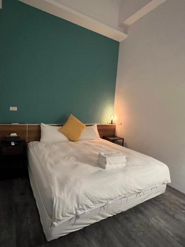 a bedroom with a white bed with a green wall at Waiting Homestay in Taitung City