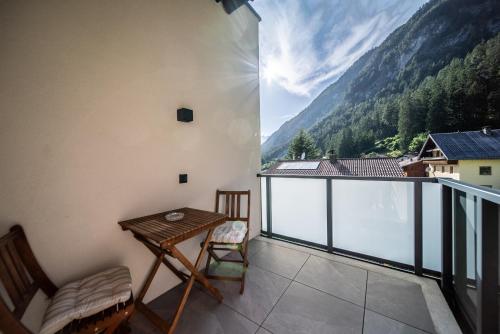 a balcony with a table and chairs and mountains at Appartements Tyrol in Pettneu am Arlberg