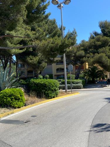 une rue vide devant un bâtiment avec des arbres dans l'établissement Studio tout confort 100m plage, à Saint-Mandrier-sur-Mer