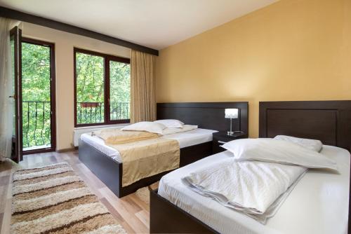 duas camas num quarto com duas janelas em Pensiunea Popasul Ursilor em Chişcău