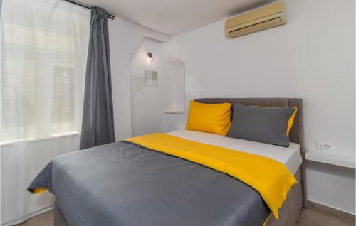 a bedroom with a bed with yellow and gray pillows at Gorgeous Home In Rab With House Sea View in Rab