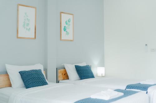 fila de camas blancas en una habitación con almohadas azules en Annahouse en Chiang Rai