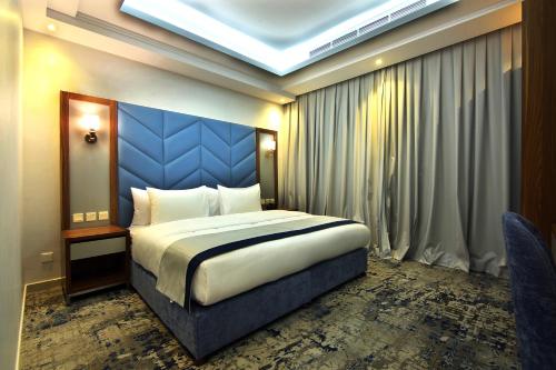 a bedroom with a king sized bed with a blue headboard at La Richy Jeddah in Jeddah