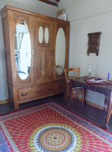 a room with a dresser and a table and a rug at Jaloersplek Victorian On Vaal Main House in Parys
