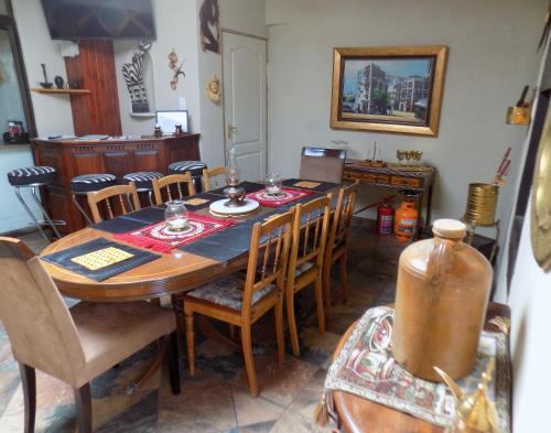 a dining room with a wooden table and chairs at Jaloersplek / Victorian On Vaal in Parys