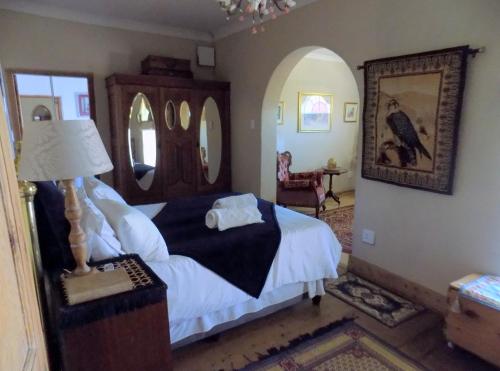 a bedroom with a bed and a table with a lamp at Jaloersplek Victorian On Vaal Main House in Parys