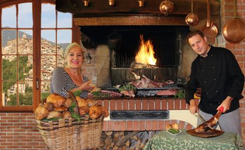 a man and a woman standing in front of a brick oven at La Favorita Apricale B&B & Ristorante in Apricale