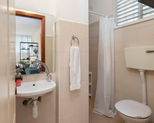 La salle de bains est pourvue de toilettes, d'un lavabo et d'un miroir. dans l'établissement Downtown Beach Apartment, à Tel Aviv
