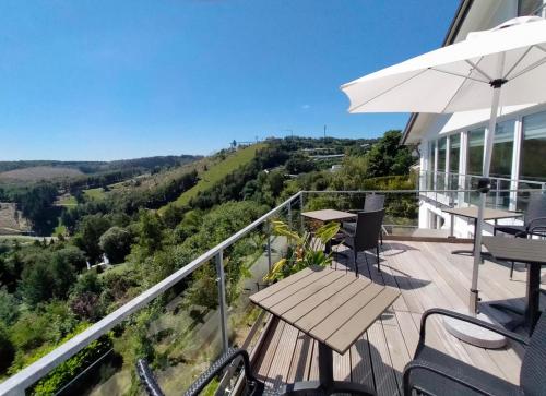 uma varanda com uma mesa e cadeiras e um guarda-sol em Landhotel Fernsicht em Winterberg