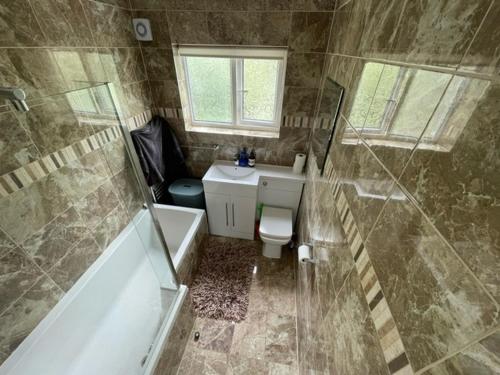 a bathroom with a tub and a toilet and a sink at Family home with easy commute to London! in Croydon