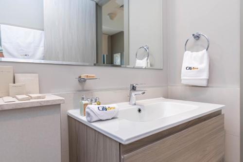 ein weißes Badezimmer mit einem Waschbecken und einem Spiegel in der Unterkunft CitiHome- Business Bay in Dubai