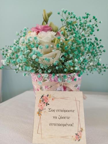 a bouquet of flowers in a vase with a sign at Theodora Rooms in Poros