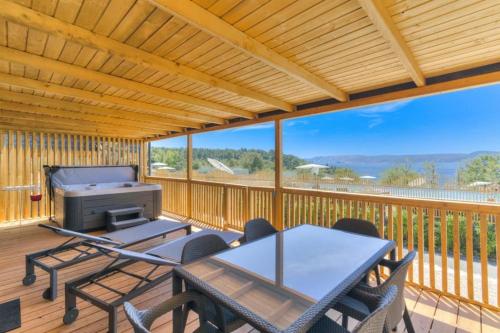 eine Terrasse mit einem Tisch und Stühlen sowie einem Grill auf einer Terrasse in der Unterkunft MOBILE HOMES SELCE - ALPE JADRAN MOBIL 641 in Selce